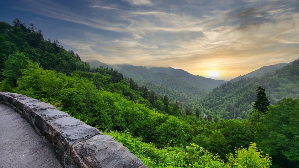 Uitzicht vanaf een stenen muurtje over glooiende beboste bergen van de Great Smoky Mountains bij zonsopgang