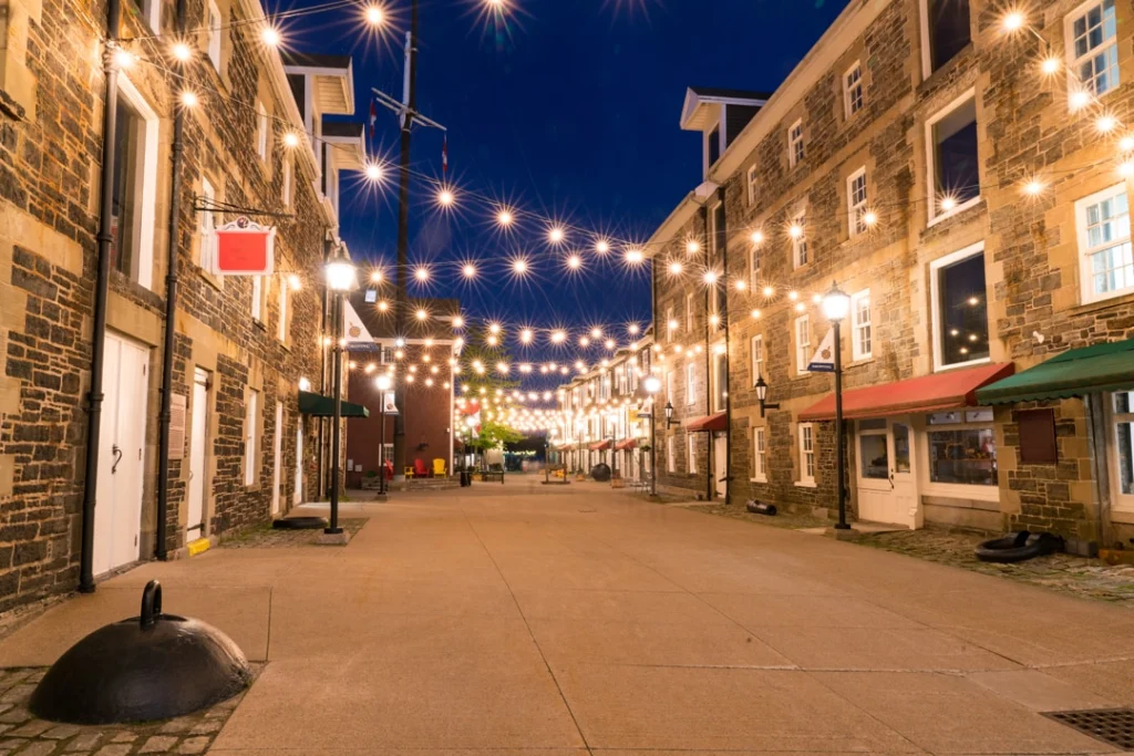 Straat tussen stenen pakhuisgebouwen met slingers van lichtjes erboven in de historische wijk Historic Properties in Halifax bij nacht