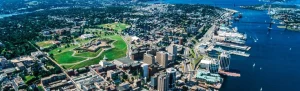 Luchtfoto van Halifax met de groene sterschans van de Citadel, hoogbouw in het centrum en drukke haven met een brug over het water op de achtergrond
