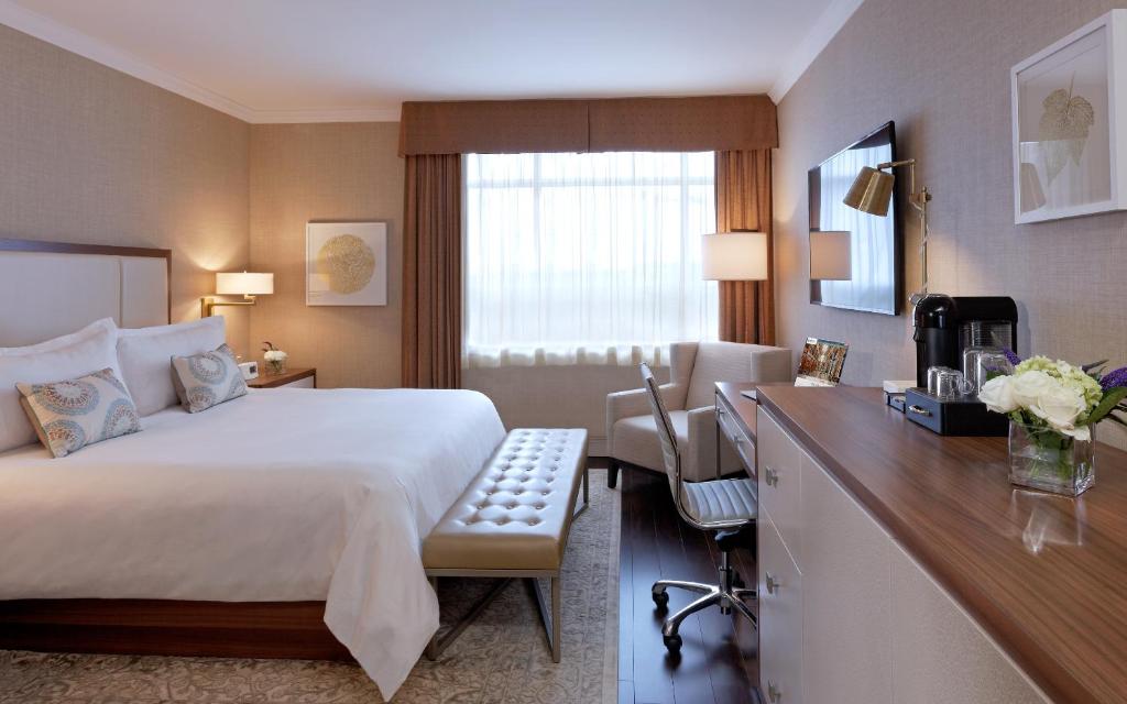 Woonkamer van een hotelsuite met een grijze bank, fauteuils, een open haard en een bureau met laptop