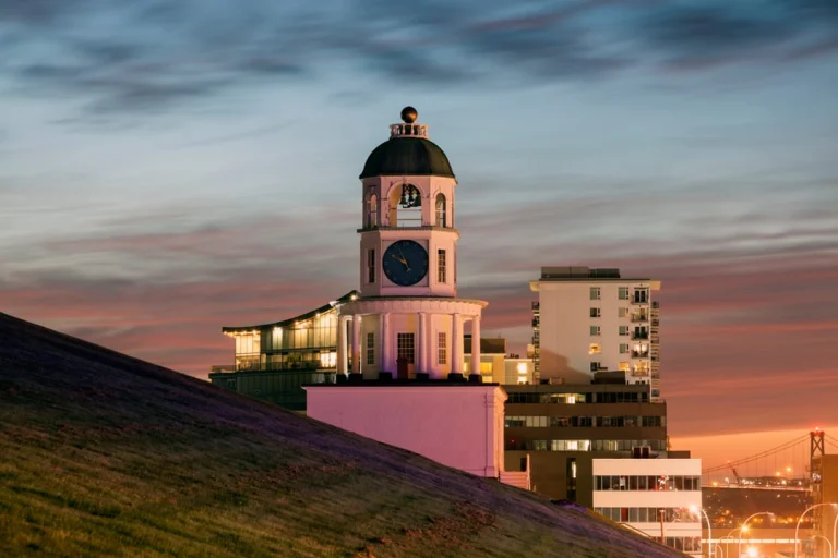 De witte klokkentoren met koepeldak van de Old Town Clock in Halifax steekt af tegen een roze en blauwe avondlucht met de stad op de achtergrond
