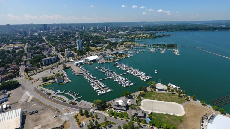 Luchtfoto van een drukke jachthaven met aangemeerde zeilboten aan de baai van Hamilton, met de stad op de achtergrond