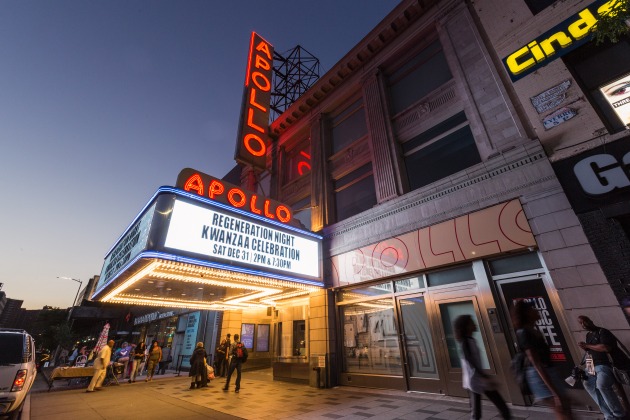 Verlichte neonreclame van het Apollo Theater met aankondiging op de luifel, gefotografeerd bij schemering in Harlem