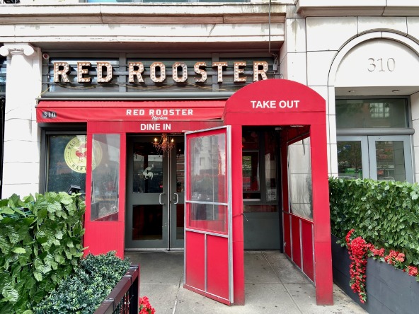 Felrode gevel van restaurant Red Rooster met neonletters en een overkapping met opschrift Take Out in Harlem