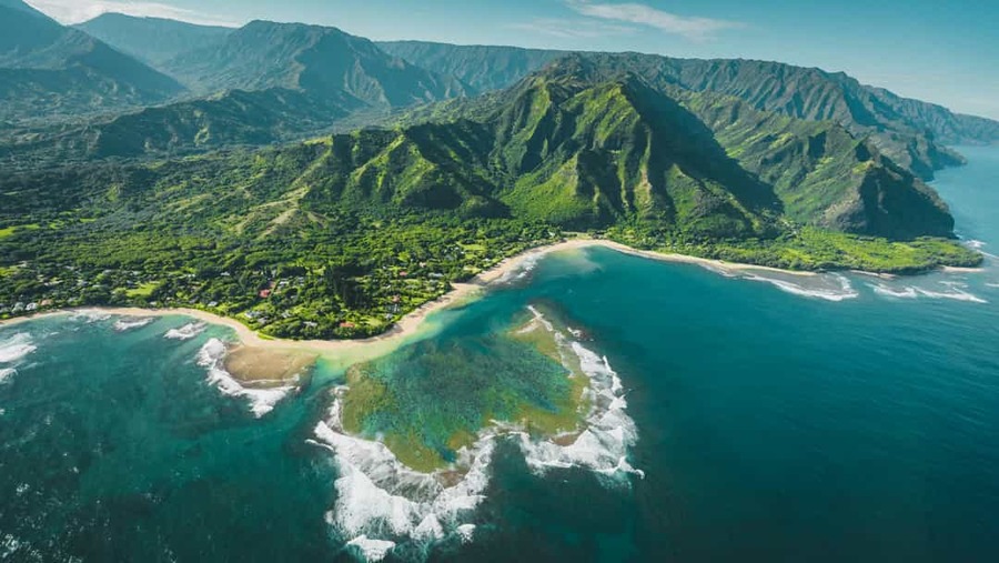 Luchtfoto van de ruige, begroeide kustlijn van Kauai in Hawaii met turquoise zee en steile bergen