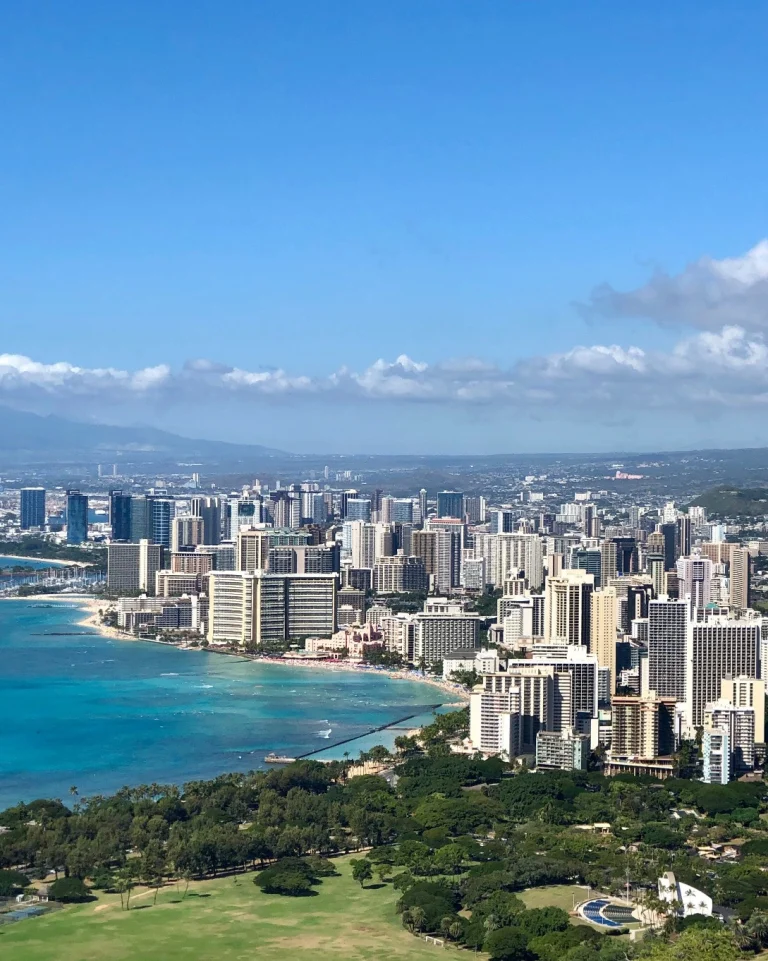 Uitzicht vanaf Diamond Head op Oahu over de wolkenkrabbers van Honolulu, het turquoise water van Waikiki Beach en groene parken op de voorgrond