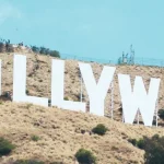 Grote witte letters van het Hollywood bord staan op een droge heuvel met antennemasten tegen een strakblauwe hemel