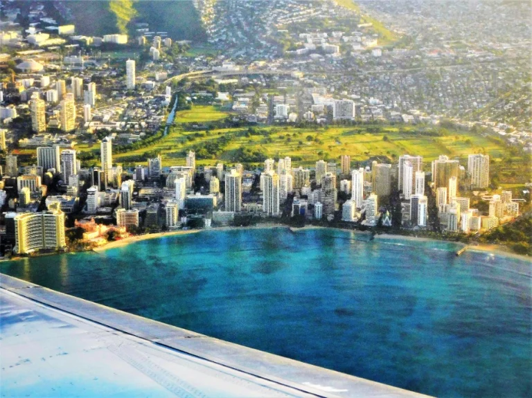 Uitzicht vanuit een vliegtuigraam op de wolkenkrabbers en kustlijn van Waikiki in Honolulu met turquoise water