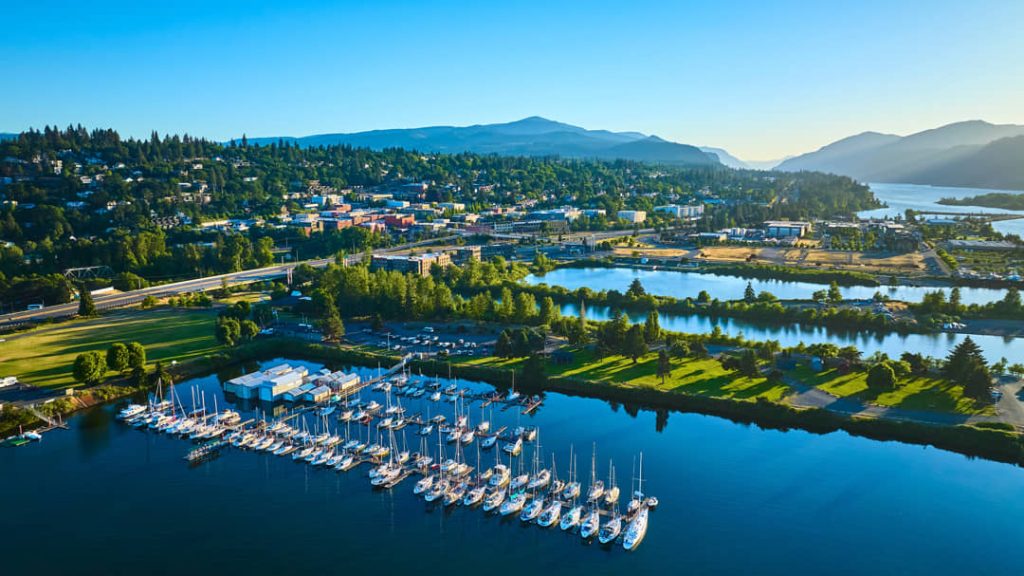 Luchtfoto van een jachthaven vol zeilboten naast de stad Hood River met bergen en de rivier op de achtergrond