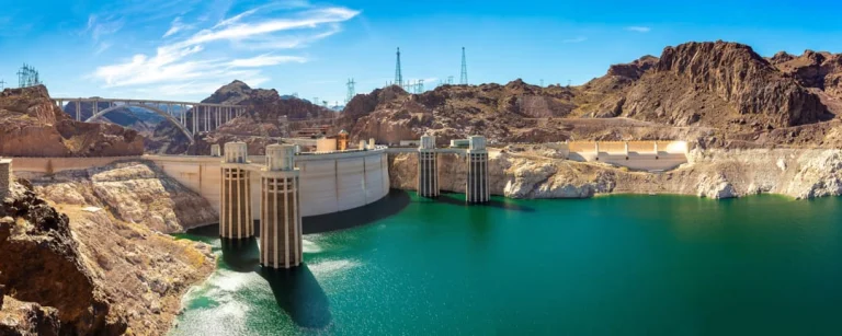 Panorama van Hoover Dam met de boogbrug op de achtergrond en turkooisblauw water van het stuwmeer