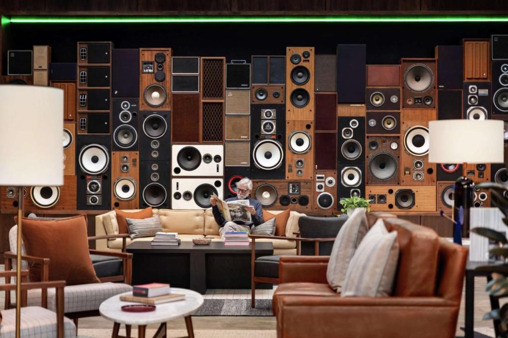 Loungeruimte met leren fauteuils en een bank voor een wand vol vintage luidsprekers