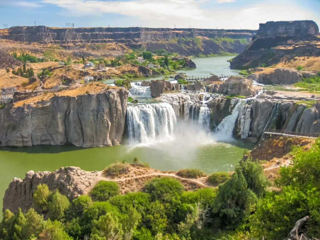 Brede waterval stort zich over rotsformaties in een diepe canyon met groene begroeiing bij Twin Falls in Idaho