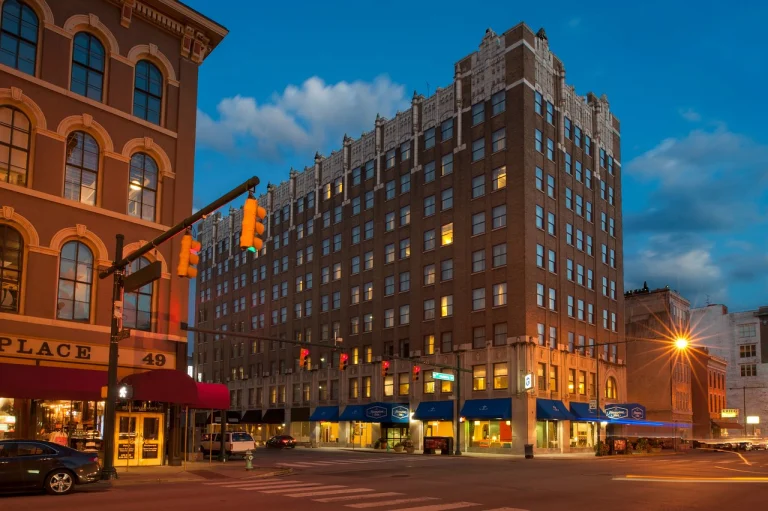 Bakstenen hotelgebouw van Hampton Inn in Indianapolis met een winkel op de begane grond aan een straathoek bij schemering