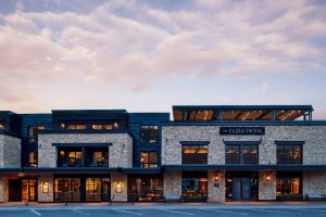 Moderne gevel van natuursteen en hout van hotel The Cloudveil in de avondschemering met verlichte ramen