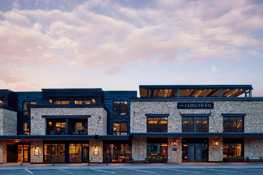 Moderne gevel van natuursteen en hout van hotel The Cloudveil in de avondschemering met verlichte ramen