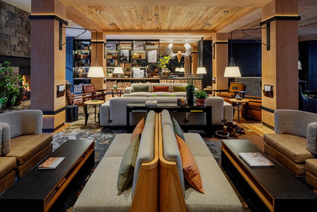 Ruime hotellounge met houten balken, banken met kussens, een open haard en een opgezette elandenkop achter de bar