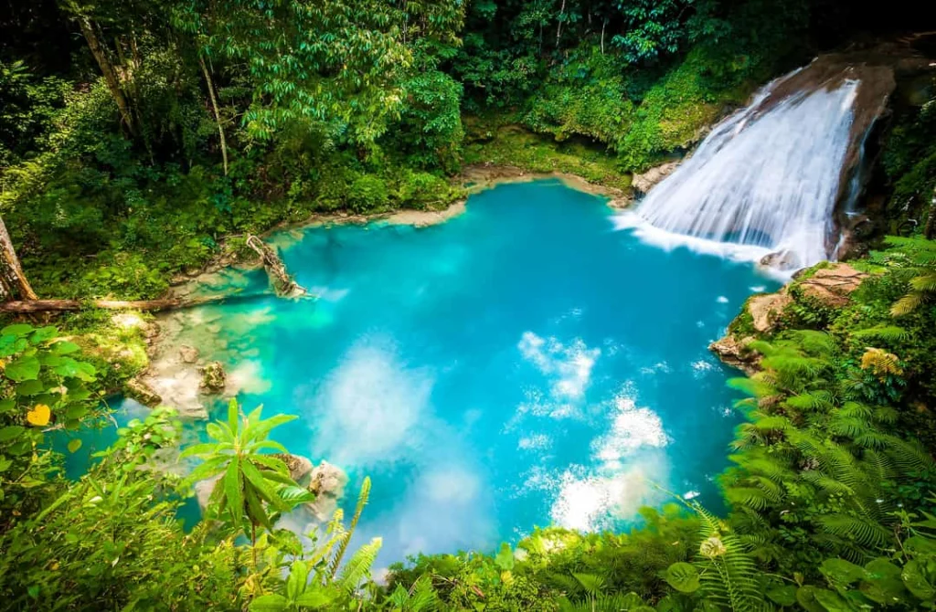 Waterval stort zich in een turquoise poel omringd door weelderig groen bij de beroemde Blue Hole op Jamaica