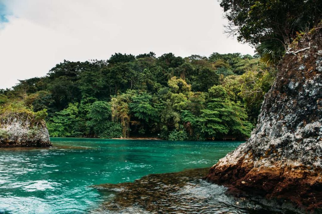 Helder turkoois water van de Blue Lagoon ligt ingesloten tussen rotsen en dichte jungle in Jamaica