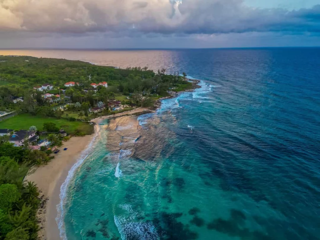 Luchtfoto van een groene kustlijn met een baaitje en turquoise water bij zonsondergang nabij Ocho Rios op Jamaica
