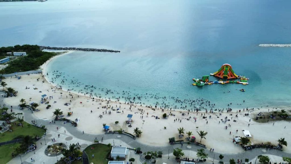 Luchtfoto van een druk zandstrand met zwemmers en een kleurrijk opblaasbaar waterpark in zee in Jamaica