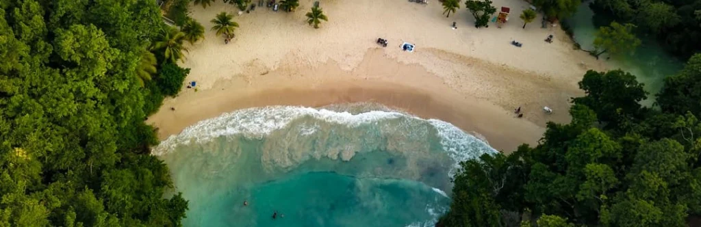 Luchtfoto van boven op een zandstrand tussen groene jungle waar witte golven breken op de kust van Jamaica