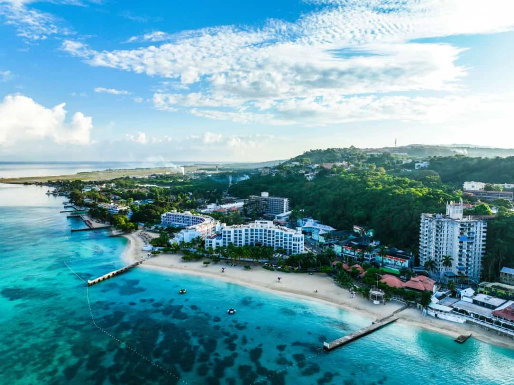 Luchtfoto van een lange zandstrand met resorts, palmbomen en helderblauw water in Montego Bay, Jamaica