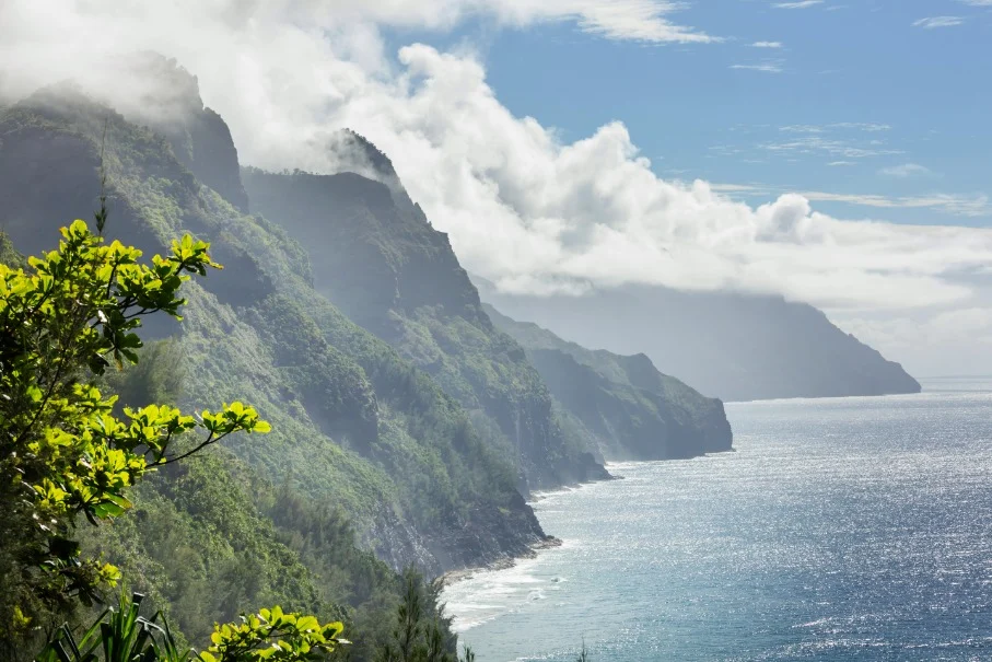 Steile, met jungle begroeide kliffen langs de Napali-kust op Kauai, gehuld in wolken boven een glinsterende blauwe oceaan