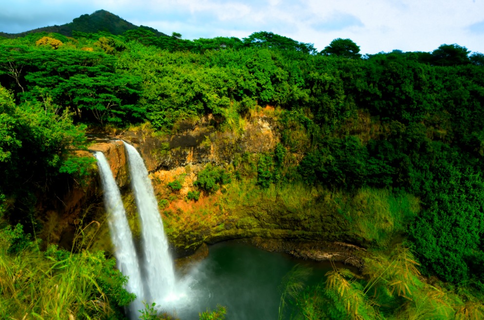 Twee parallelle watervallen storten neer in een groen begroeide vallei op het eiland Kauai in Hawaii
