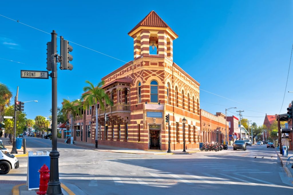 Historisch bakstenen gebouw met sierlijke toren op een straathoek met palmbomen en het straatbord Front Street in Key West