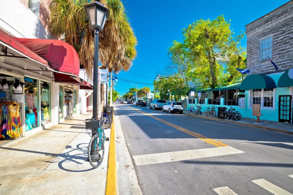 Lege straat met kleurrijke winkelpanden, luifels en palmbomen langs Duval Street in Key West, met een fiets tegen een lantaarnpaal