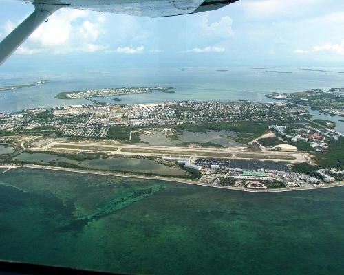 Uitzicht vanuit het raam van een klein vliegtuig over het eiland Key West met een vliegveld en omringend turkoois water