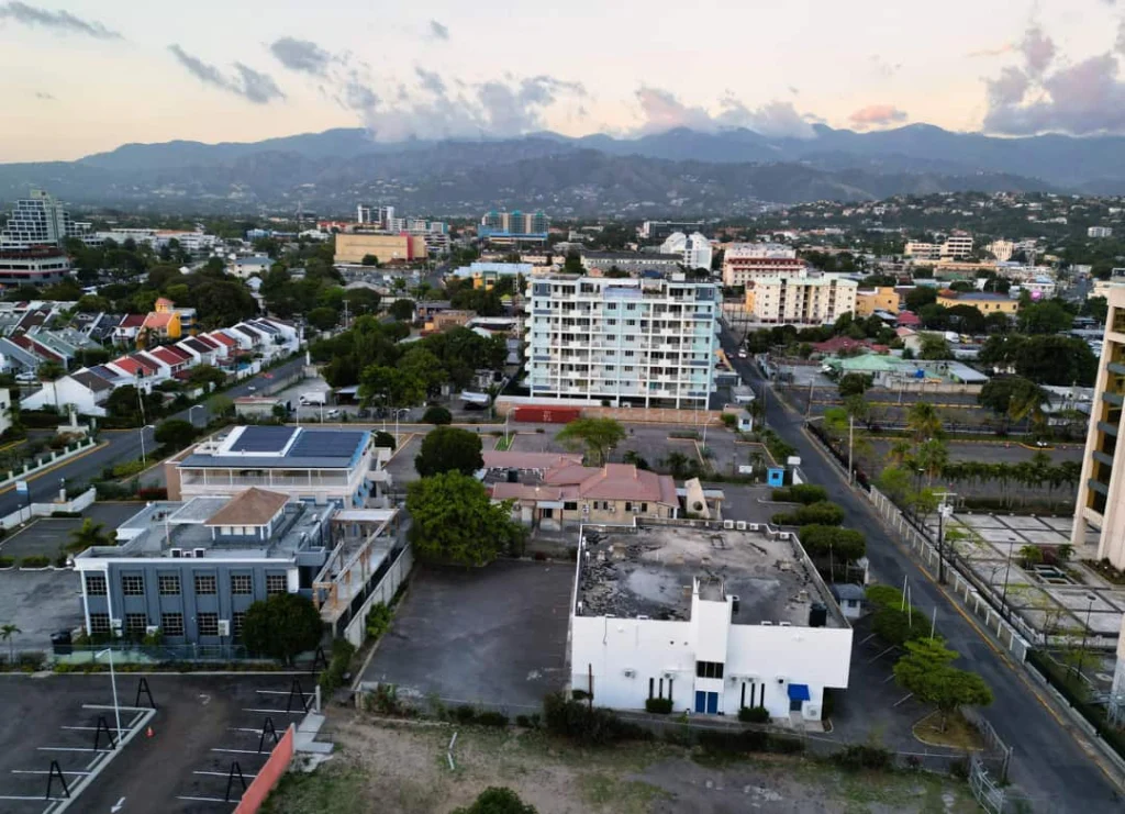 Luchtfoto van gebouwen en straten in New Kingston met bergen op de achtergrond bij een zachte avondlucht