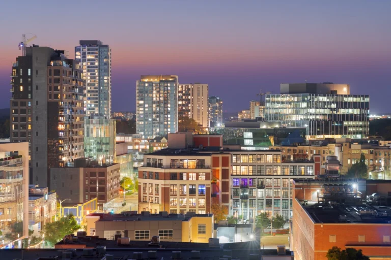 Verlichte hoge gebouwen en appartementen van Kitchener tegen een paarse avondlucht na zonsondergang