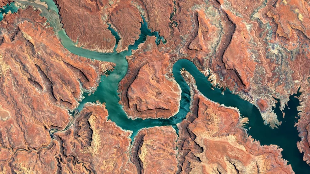 Luchtfoto van turquoise waterarmen die zich vertakken tussen roodbruine rotsformaties bij Lake Powell