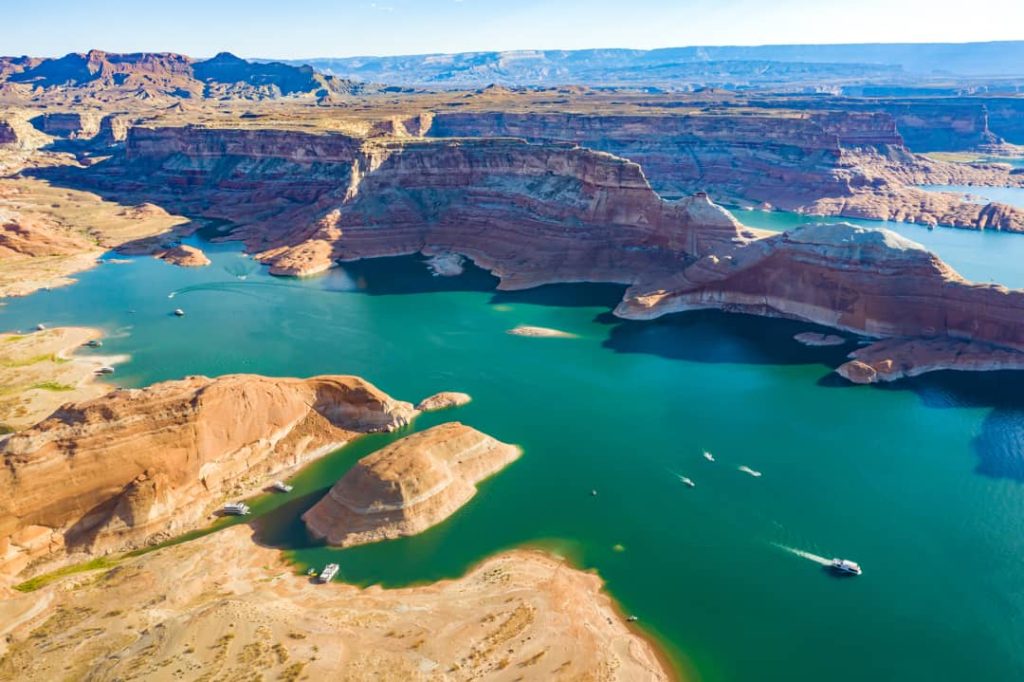 Luchtfoto van het groenblauwe water van Lake Powell met verspreide boten tussen rotsachtige eilanden en canyons
