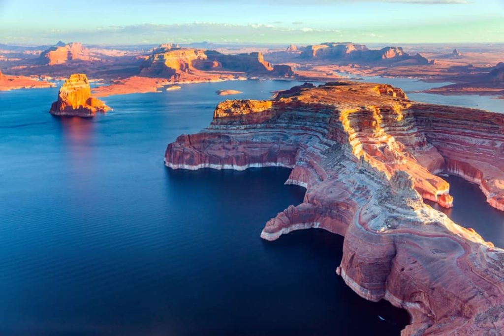 Luchtfoto van het blauwe water van Lake Powell met de losstaande rotsformatie Lone Rock en rode canyonwanden op de achtergrond