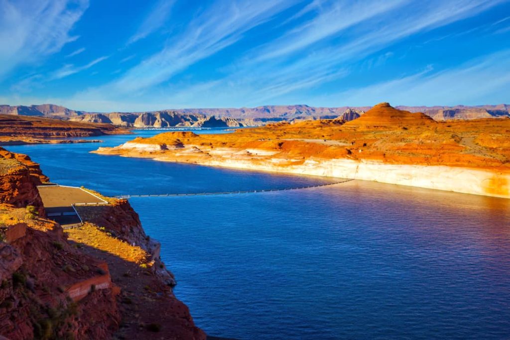 Luchtfoto van rode rotsoevers rond het blauwe water van Lake Powell met een uitzichtpunt op de voorgrond