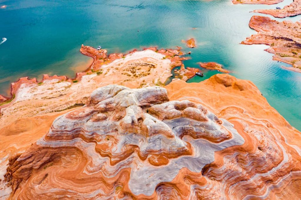Luchtfoto van een opvallend gestreepte zandsteenformatie omringd door turquoise water bij Lake Powell