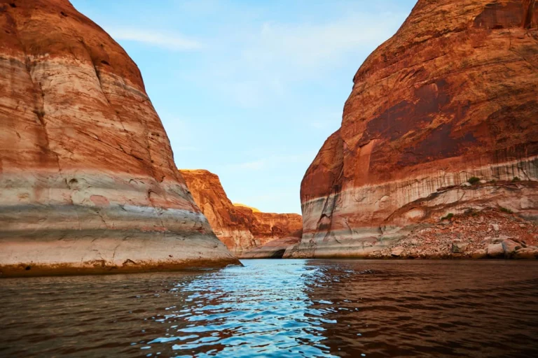 Vaartocht tussen hoge roodwit gestreepte zandsteenwanden met kalm blauw water van Lake Powell