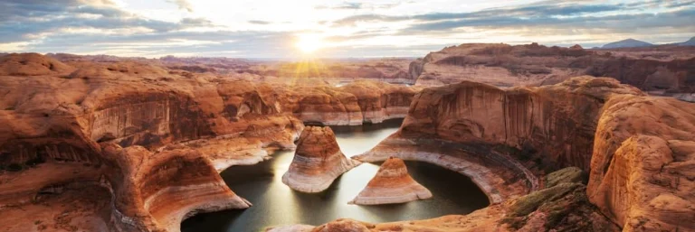 Zonsopgang boven de roodbruine rotsformaties en het stille water van Lake Powell in Arizona