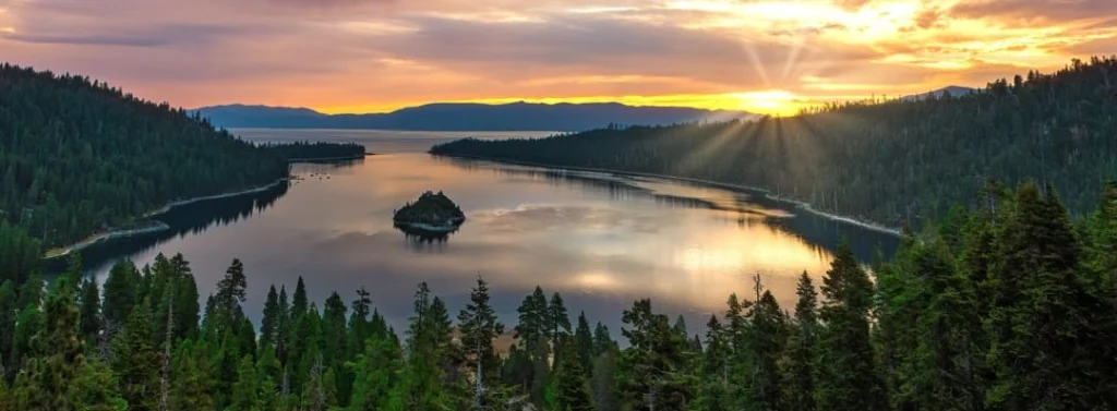 Panoramisch uitzicht op Emerald Bay bij Lake Tahoe met een klein eilandje in het meer tijdens een kleurrijke zonsondergang, omringd door dennenbossen