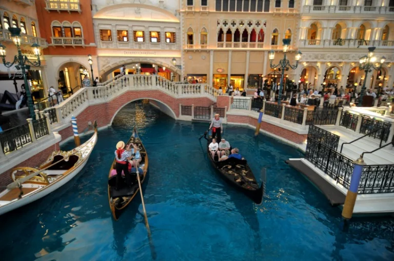 Gondeliers varen met toeristen over een kunstmatig kanaal onder een stenen brug in het overdekte winkelcentrum van hotel The Venetian in Las Vegas
