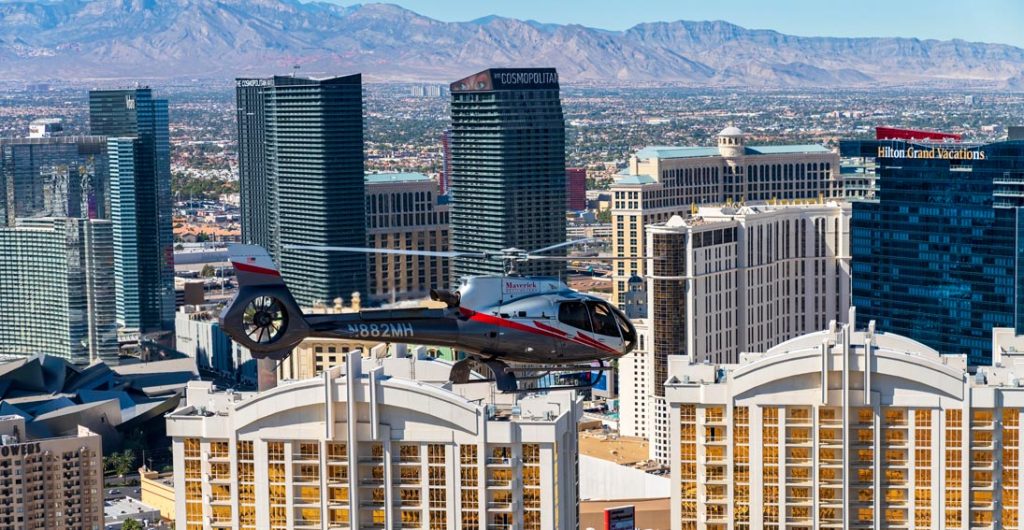 Een helikopter vliegt boven de hotels van de Strip in Las Vegas met bergen op de achtergrond overdag