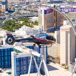 Een helikopter vliegt boven Las Vegas langs het reuzenrad High Roller met hotels als Harrah's en The Mirage op de achtergrond