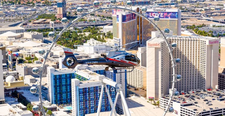Een helikopter vliegt boven Las Vegas langs het reuzenrad High Roller met hotels als Harrah's en The Mirage op de achtergrond