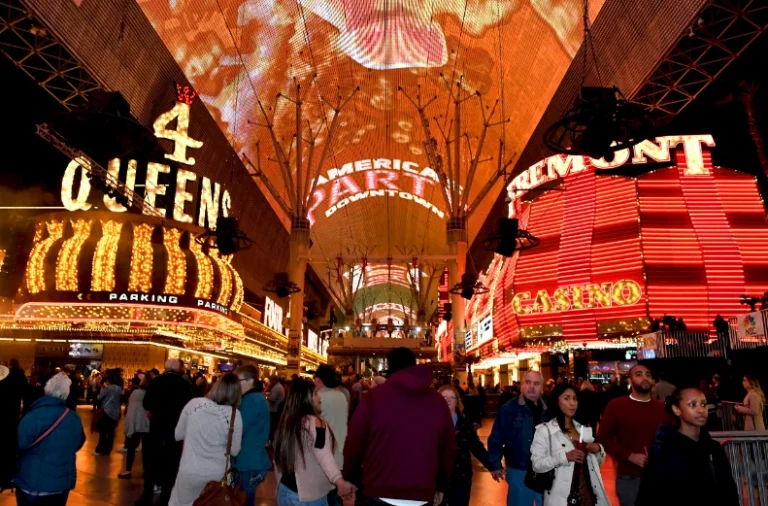 Drukke overdekte winkelstraat in Las Vegas vol felle neonreclames van casino's terwijl mensen 's avonds over Fremont Street lopen