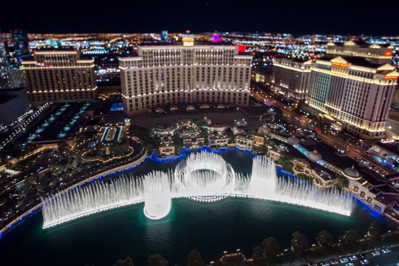 Vogelvluchtperspectief op de verlichte waterfonteinen van het Bellagio meer omringd door hotels en de felverlichte Las Vegas Strip bij nacht