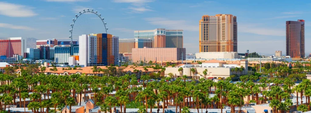 De skyline van Las Vegas met het grote High Roller reuzenrad en hotels boven een rij palmbomen overdag