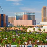 De skyline van Las Vegas met het grote High Roller reuzenrad en hotels boven een rij palmbomen overdag
