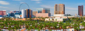 De skyline van Las Vegas met het grote High Roller reuzenrad en hotels boven een rij palmbomen overdag